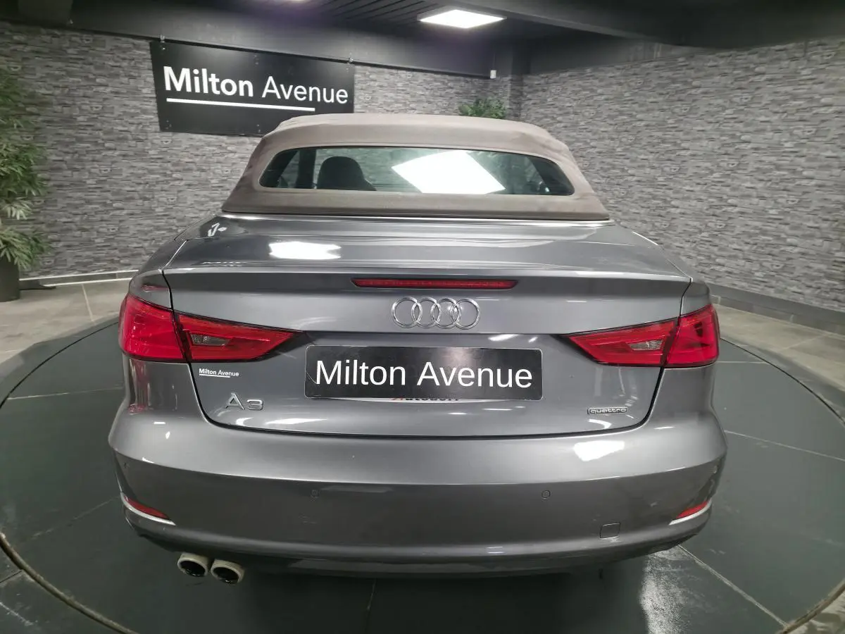 Vue arrière d'un Audi A3 Cabriolet gris avec capote beige et double sortie d'échappement à gauche.