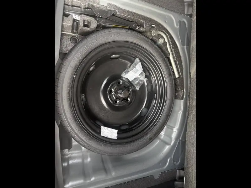 Vue rapprochée de la roue de secours noire dans le coffre d'une CUPRA Formentor bleu 2025, avec outils de changement visibles.