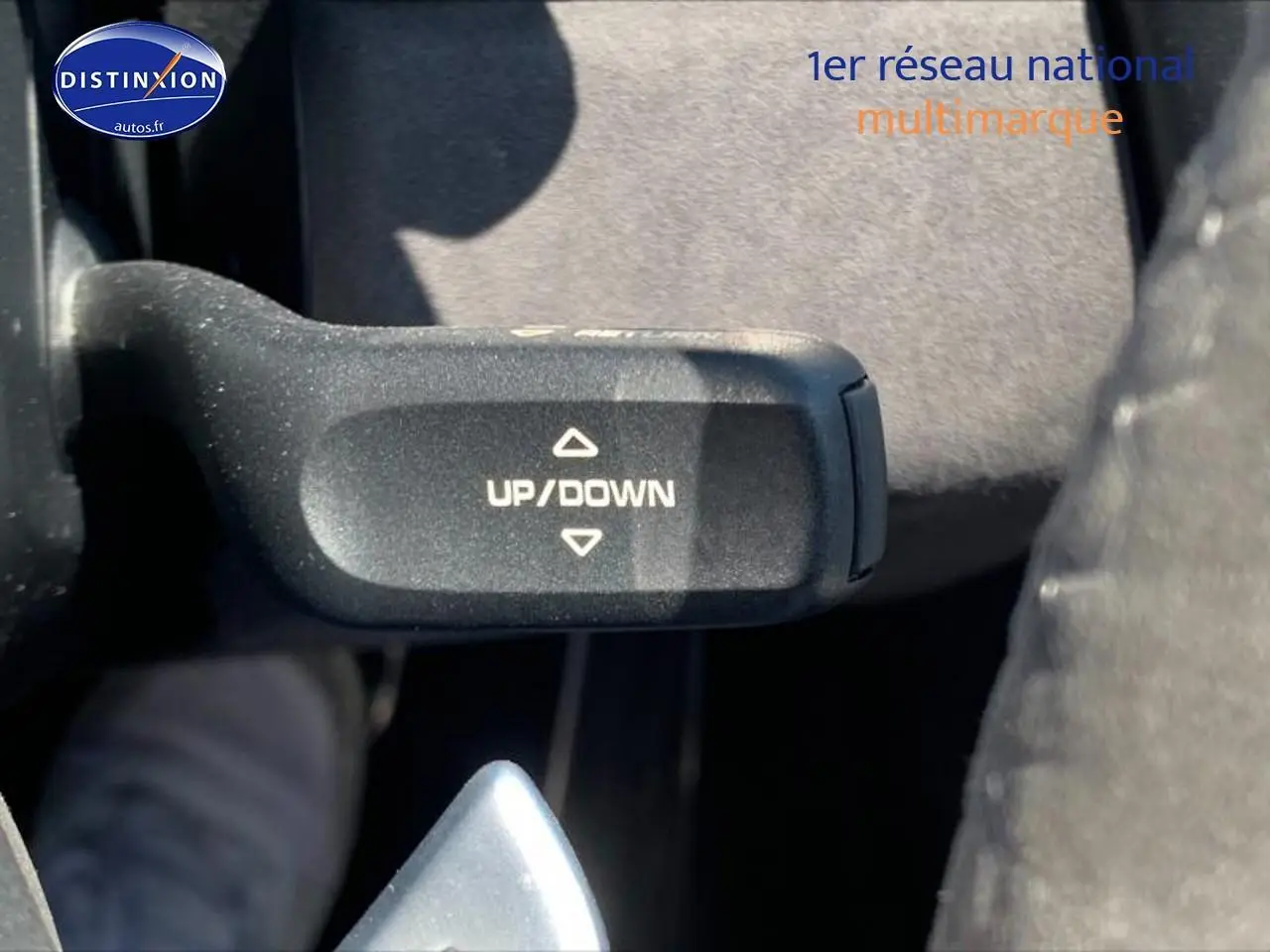 Gros plan sur la commande de palettes au volant marquée "UP/DOWN" dans l'habitacle d'une Porsche Boxster rouge.