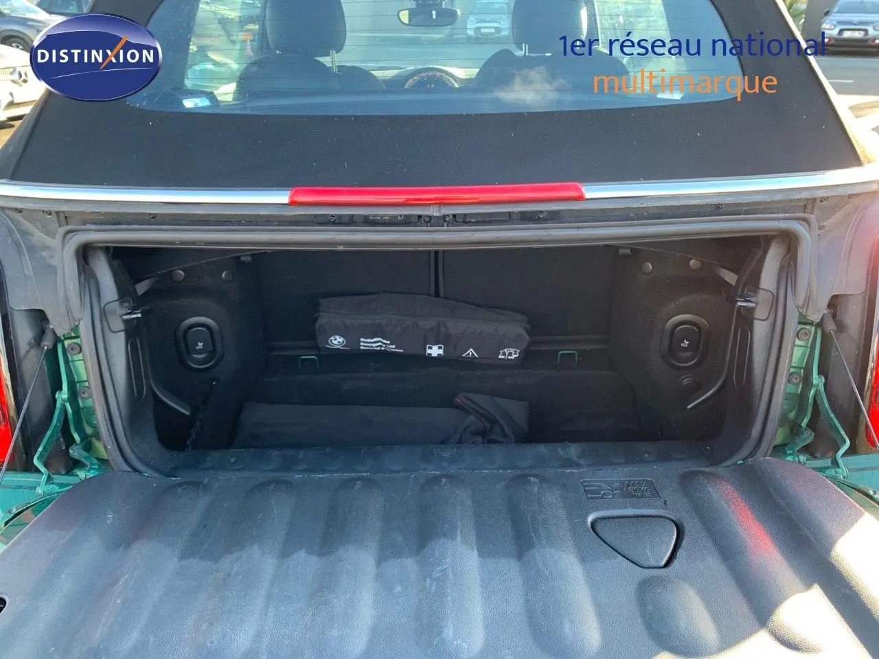 Coffre ouvert vu de l'arrière d'une MINI Cabriolet F57 2023 British Racing Green avec capote noire.