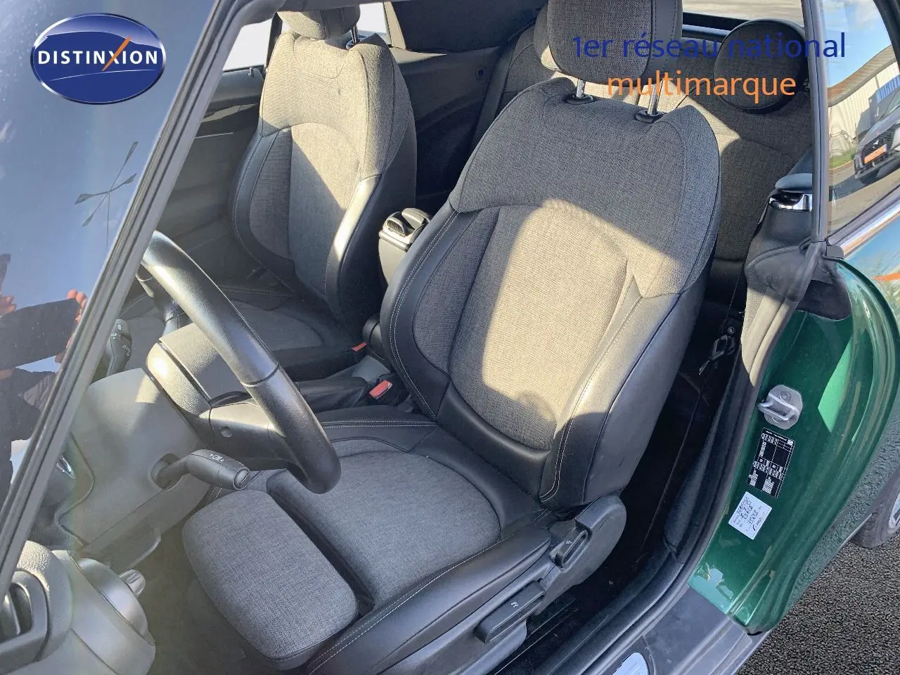 Vue intérieure côté conducteur d'une MINI Cabriolet British Racing Green avec sièges tissu et cuir noir.