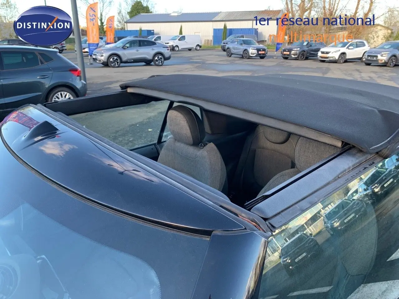 Vue arrière rapprochée d'une MINI Cabriolet British Racing Green avec capote noire partiellement ouverte.