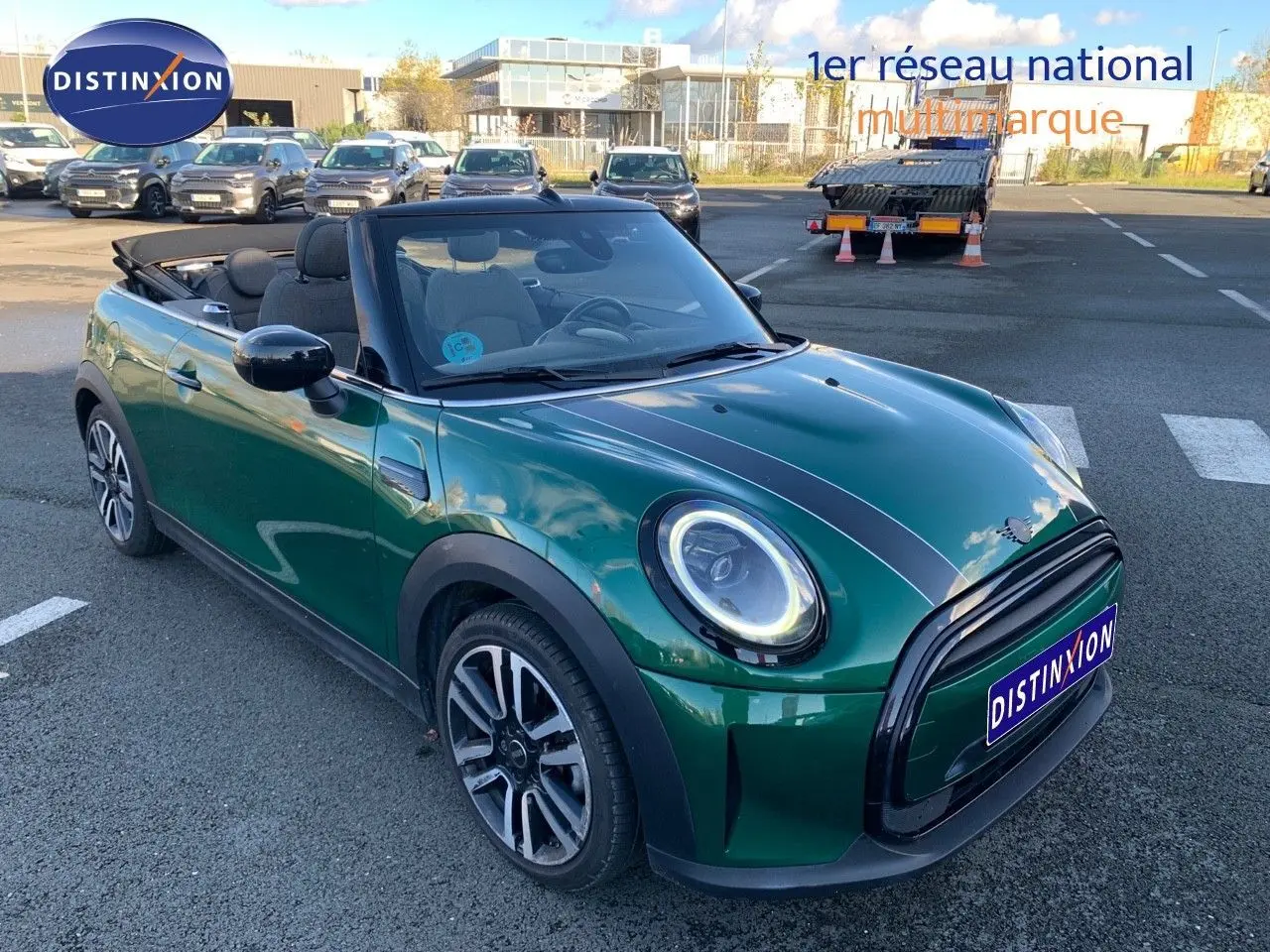 Mini Cabriolet F57 2023 British Racing Green vue 3/4 avant avec capote ouverte et bandes noires sur le capot.