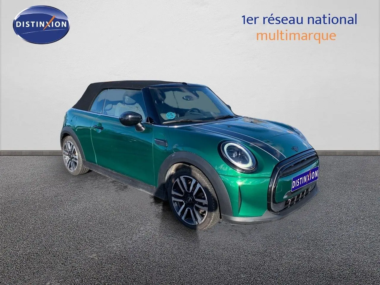Vue 3/4 avant gauche d'une MINI Cabriolet 2023 British Racing Green avec toit noir fermé et jantes bi-ton.