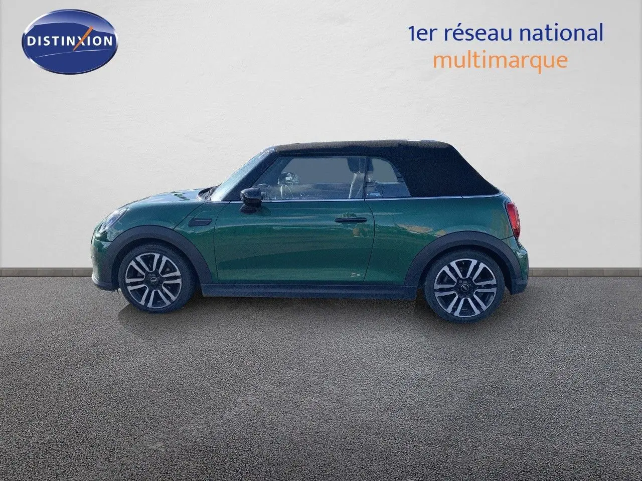 Profil côté gauche d'une MINI Cabriolet 2023 British Racing Green avec toit noir fermé sur fond neutre.
