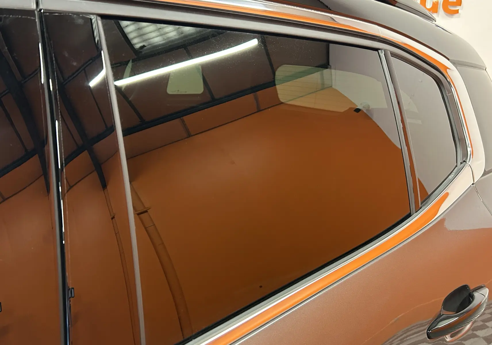 Gros plan sur la vitre arrière côté droit du Citroën C5 Aircross gris platinium métal avec toit noir, reflet intérieur visible.