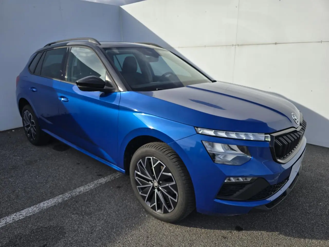 Vue 3/4 avant gauche d'un Skoda Kamiq bleu racing avec toit noir et jantes alliage 17 pouces.