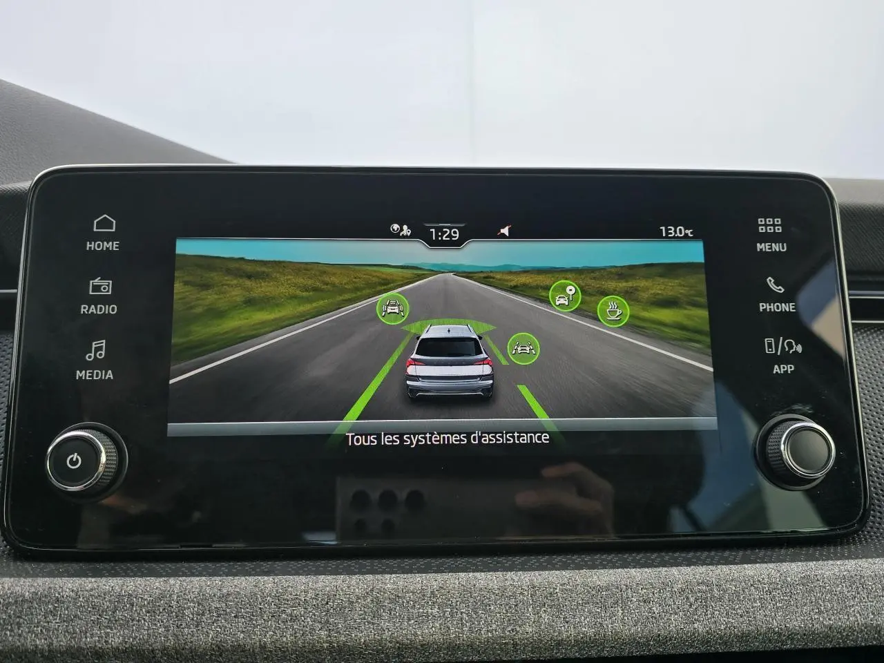 Écran central affichant l'assistance à la conduite avec vue arrière d'une Skoda Kamiq bleu racing et toit noir.