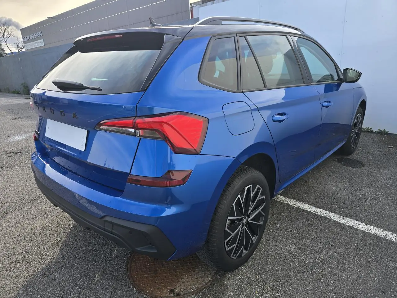 Vue 3/4 arrière droite d'un Skoda Kamiq bleu racing avec toit noir et jantes alliage 17 pouces.