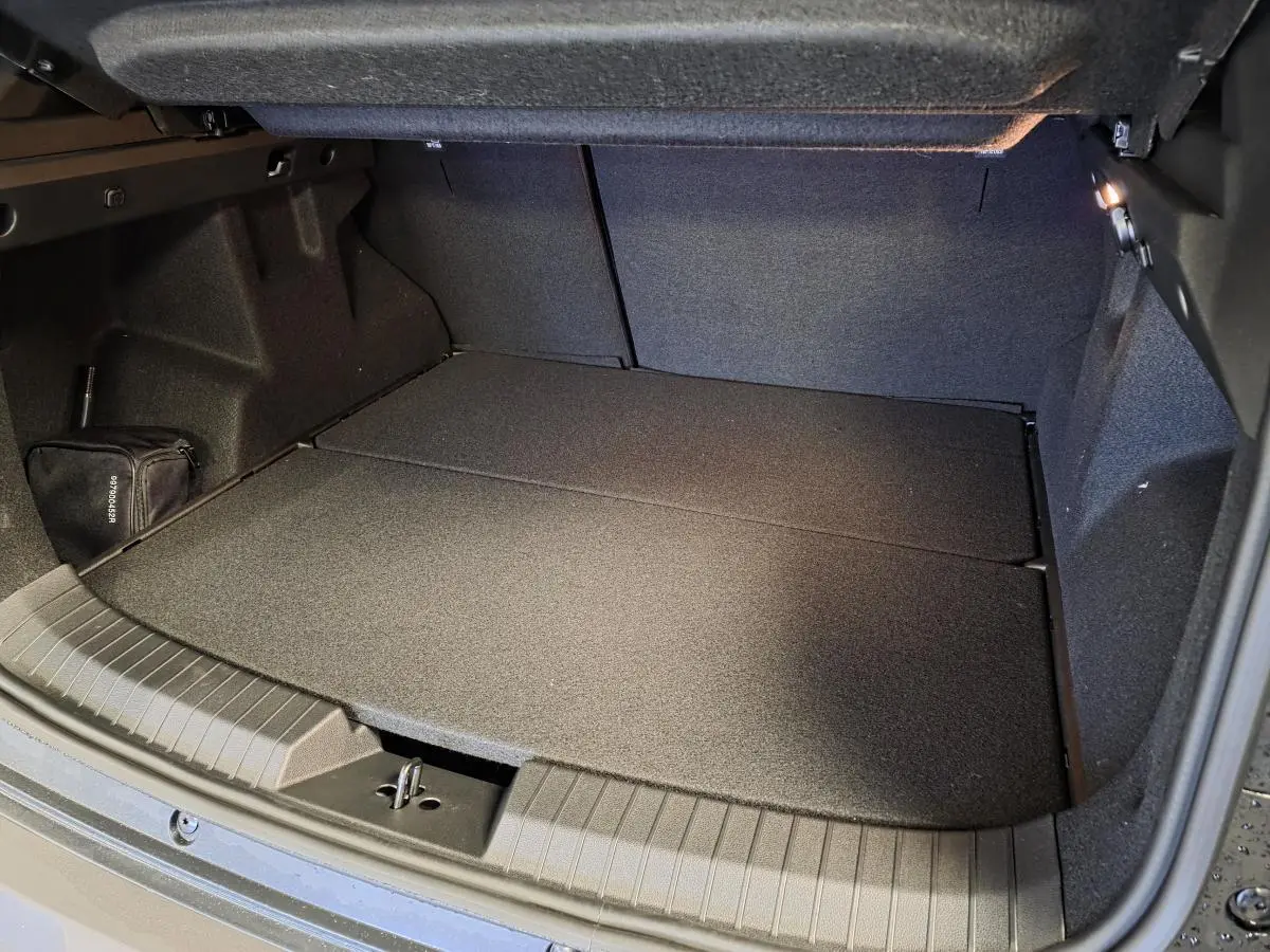 Coffre ouvert du Dacia Duster 1.6 Hybrid noir, vue plongeante montrant l’espace de rangement et la moquette noire.