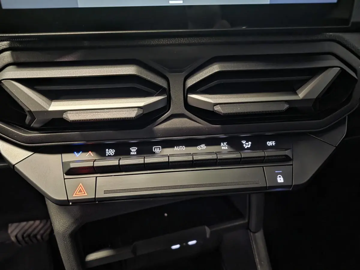 Détail des aérateurs gris acier et commandes climatisation du tableau de bord du Dacia Duster noir 2025.