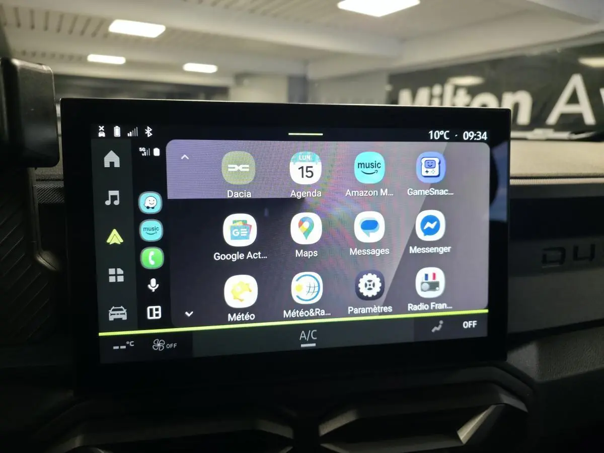 Écran tactile central du Dacia Duster 2025 affichant les applications connectées, avec tableau de bord noir en arrière-plan.