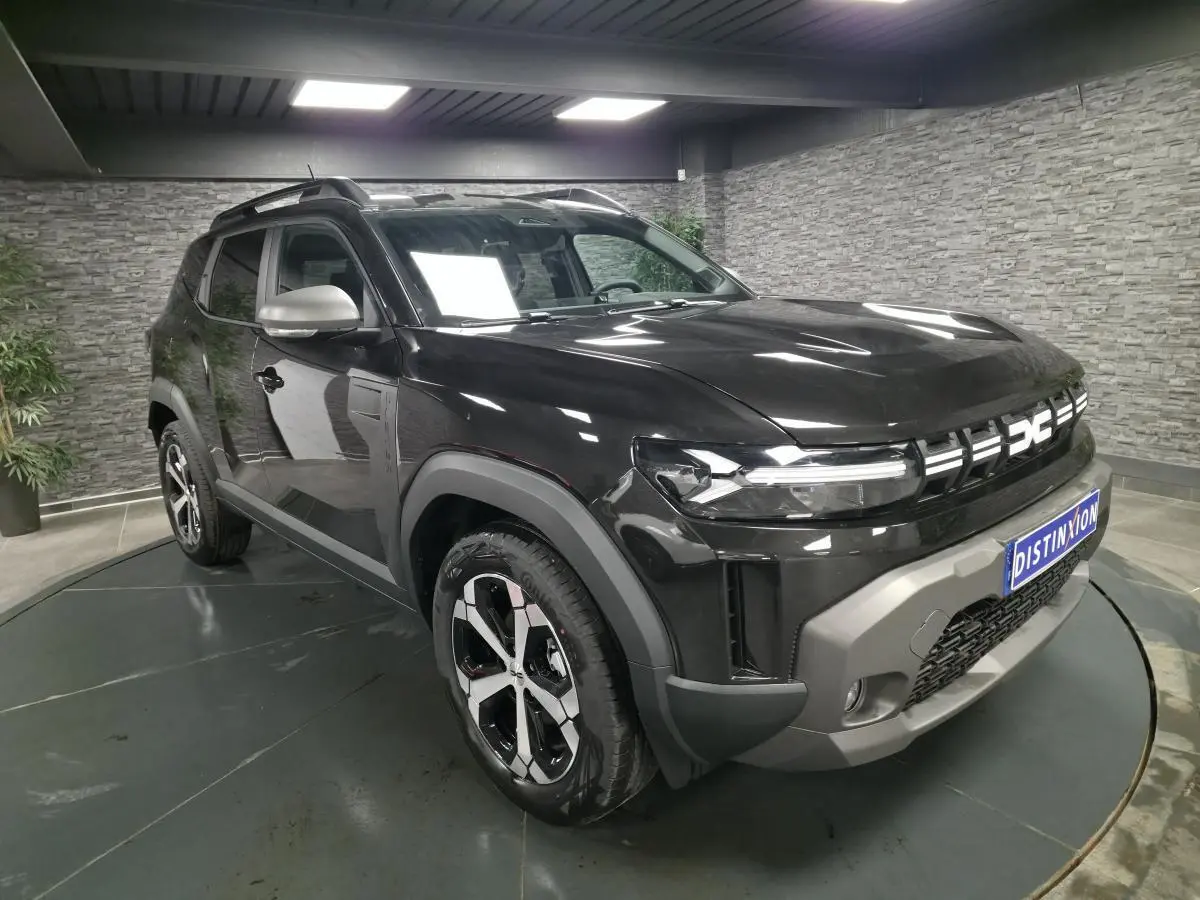 Dacia Duster 1.6 Hybrid noir nacré en 3/4 avant droit, avec jantes alliage 18 pouces et barres de toit noires.