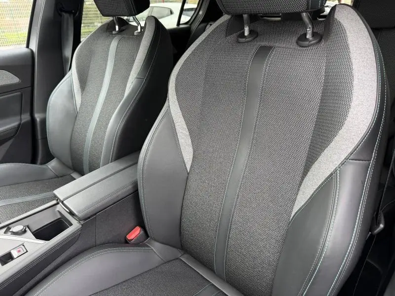 Gros plan sur les sièges avant gris mêlant tissu et cuir dans l’habitacle d’une Peugeot 308 1.2 PureTech 130ch 2024.