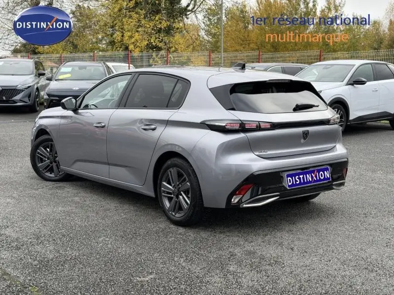 Peugeot 308 gris vue 3/4 arrière droit, feux arrière LED distinctifs et jantes alliage, stationnée en extérieur.