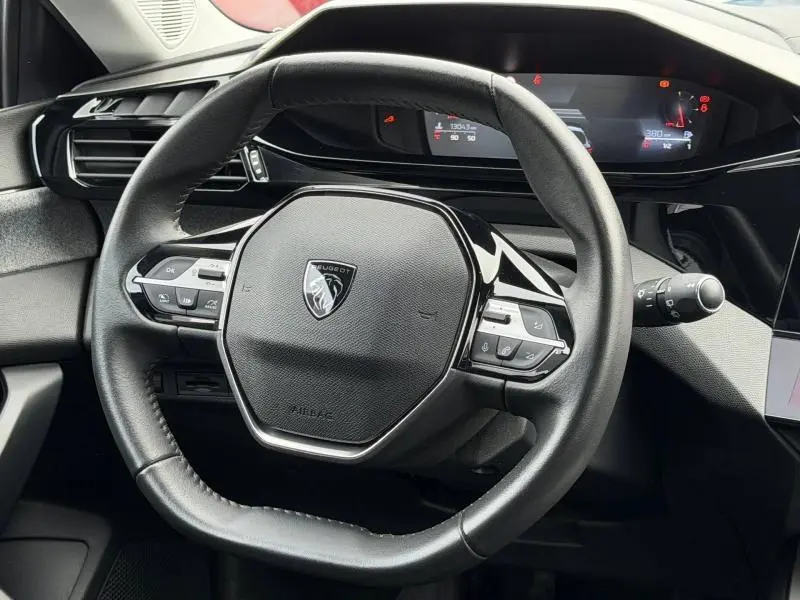 Vue rapprochée du volant cuir noir de la Peugeot 308 2024 avec commandes intégrées et tableau de bord digital.