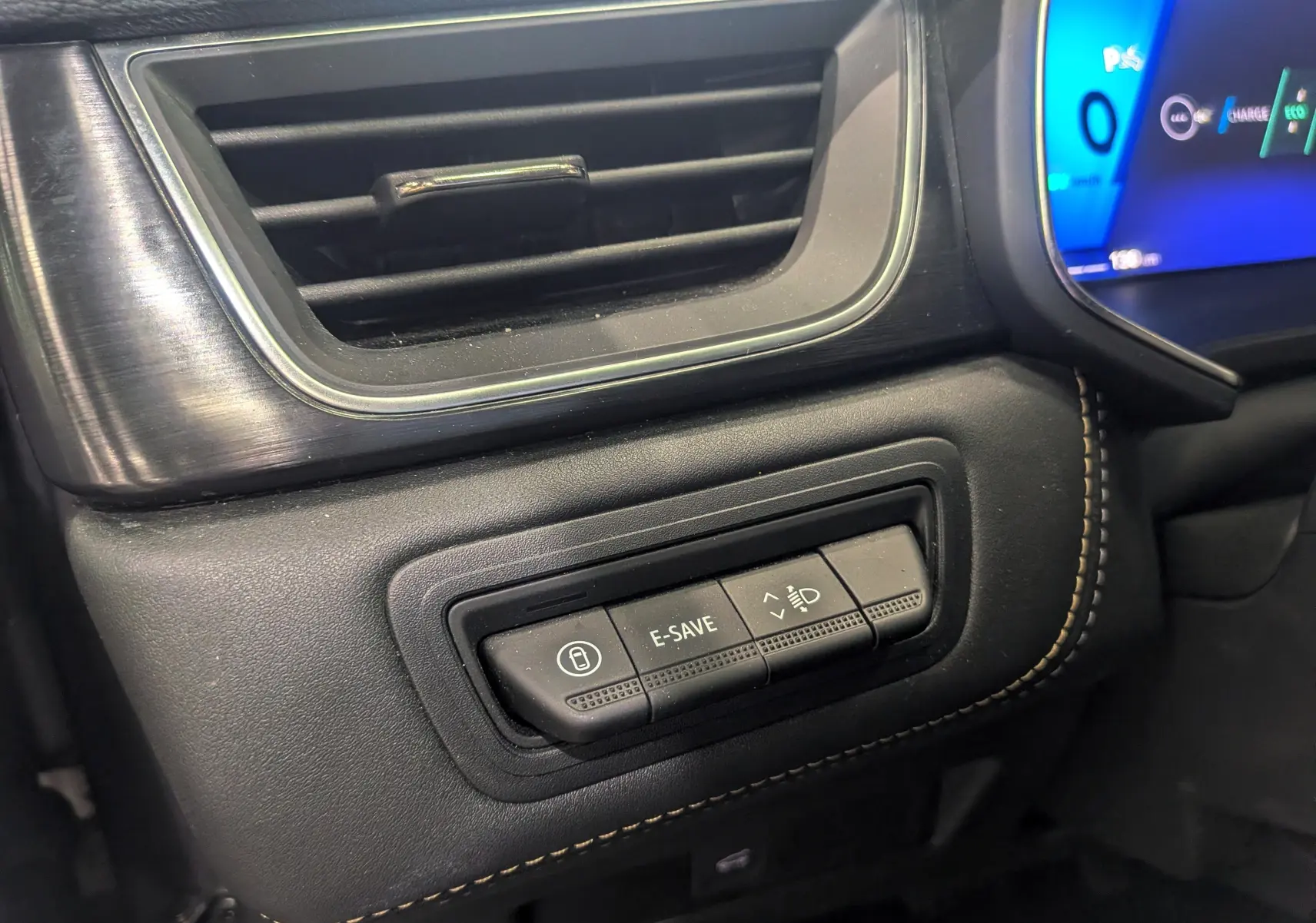 Détail du tableau de bord côté gauche du Renault Symbioz E-TECH gris, avec commandes E-SAVE et réglage des phares.