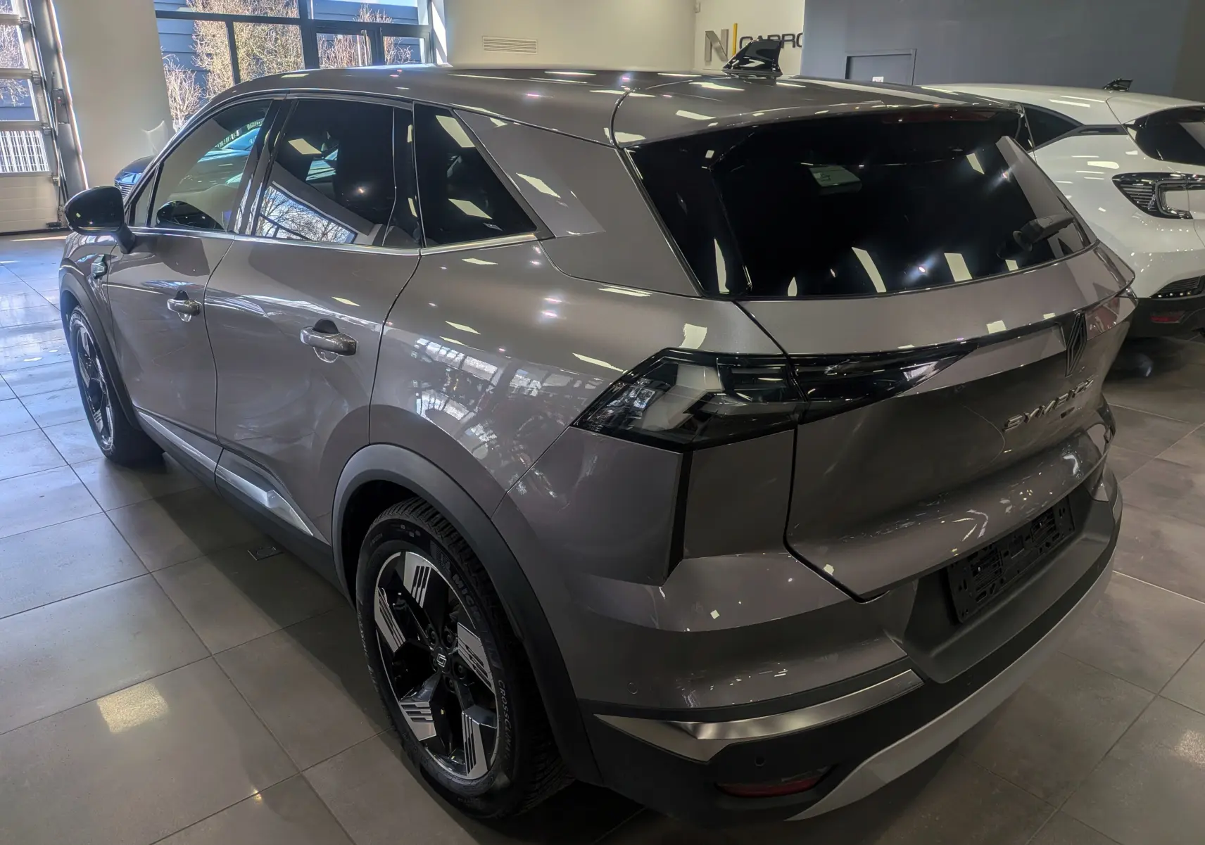 Vue 3/4 arrière droite du Renault SYMBIOZ gris Cassiopé, soulignant ses feux arrière noirs et ses jantes bicolores.