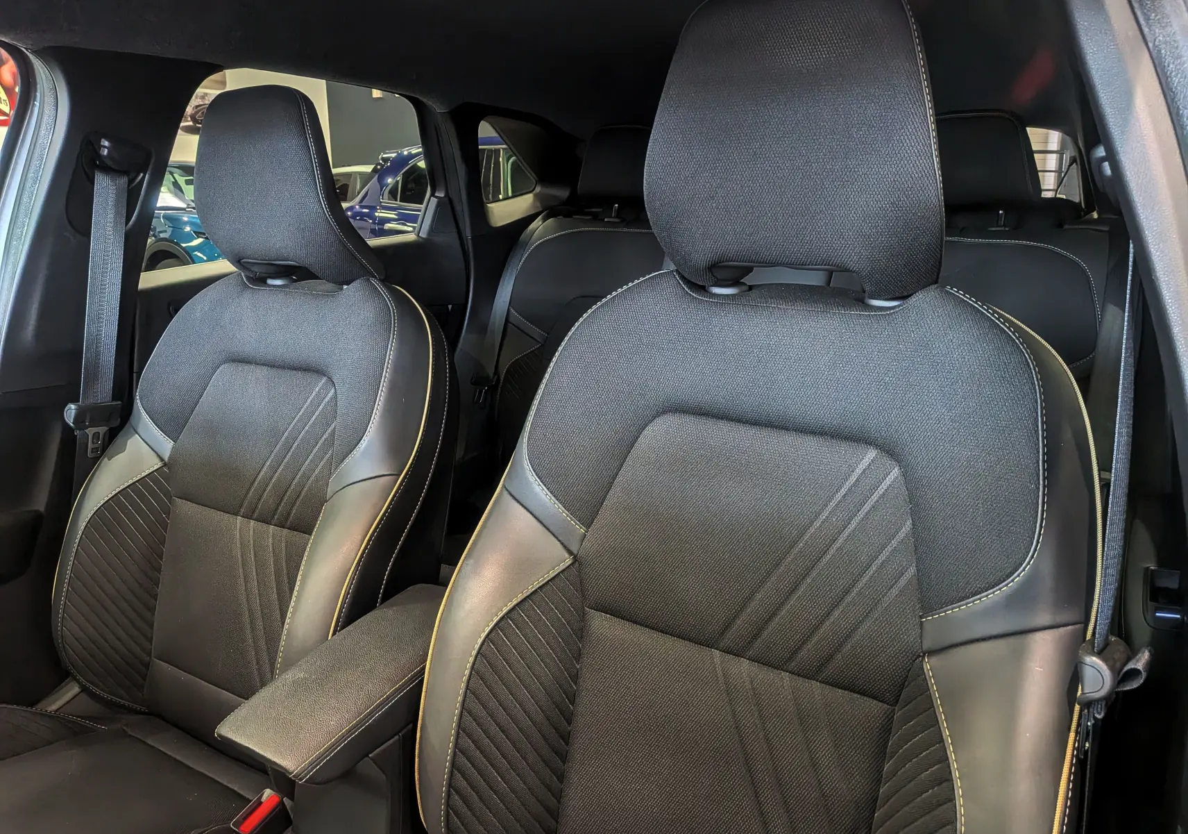 Vue intérieure rapprochée des sièges avant en tissu et cuir noir avec surpiqûres claires du Renault Symbioz E-TECH 2025.