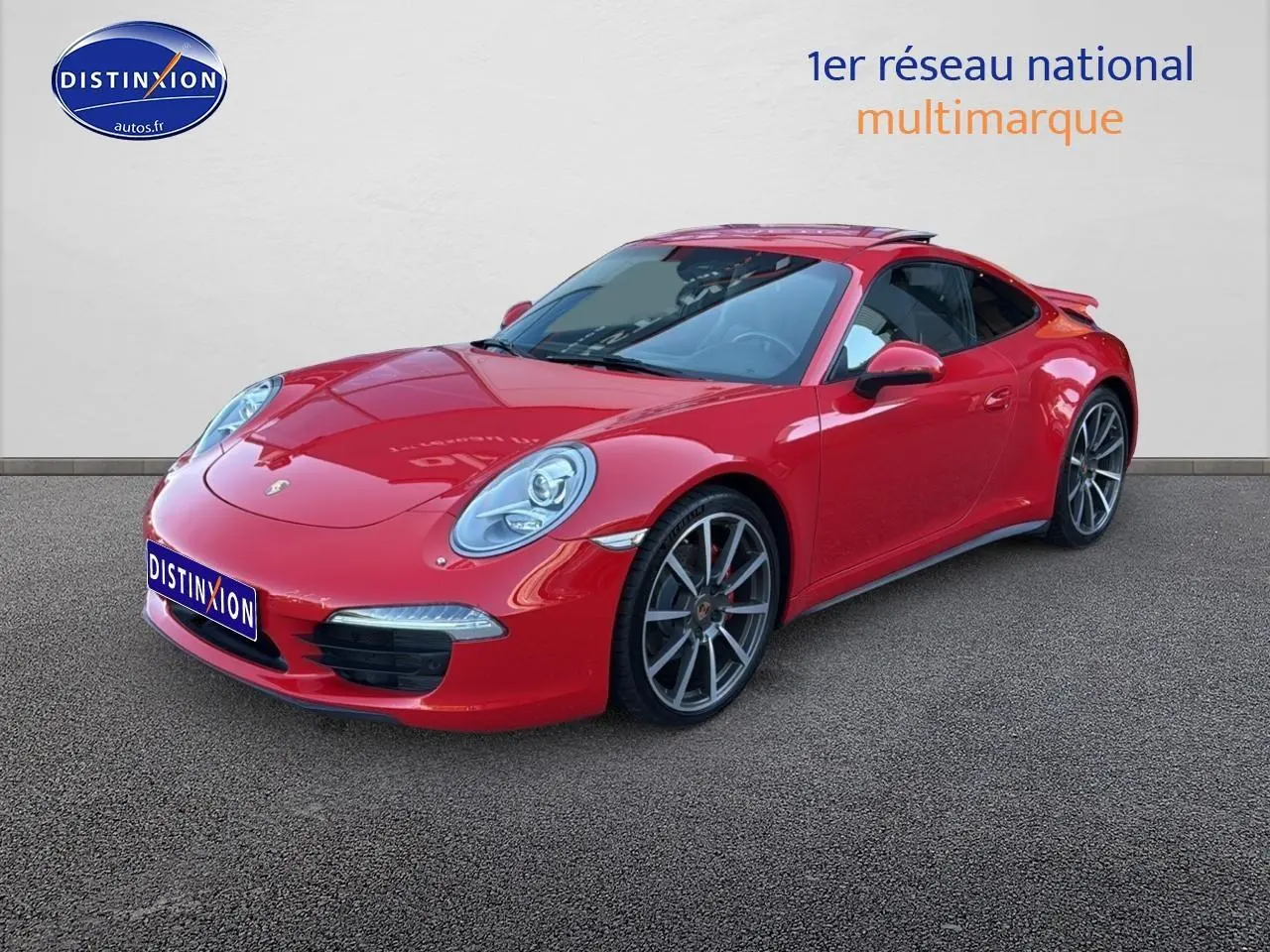 Porsche 911 (991) Carrera 4 rouge vue 3/4 avant avec jantes alu et becquet arrière visible.