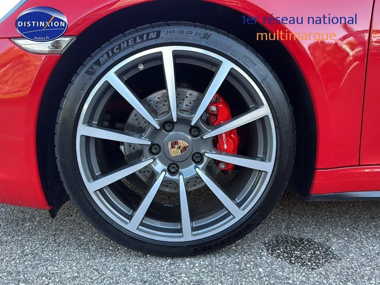 Gros plan sur la roue avant droite rouge d'une Porsche 911 (991) Carrera 4 PDK avec étrier de frein rouge et jante alu.
