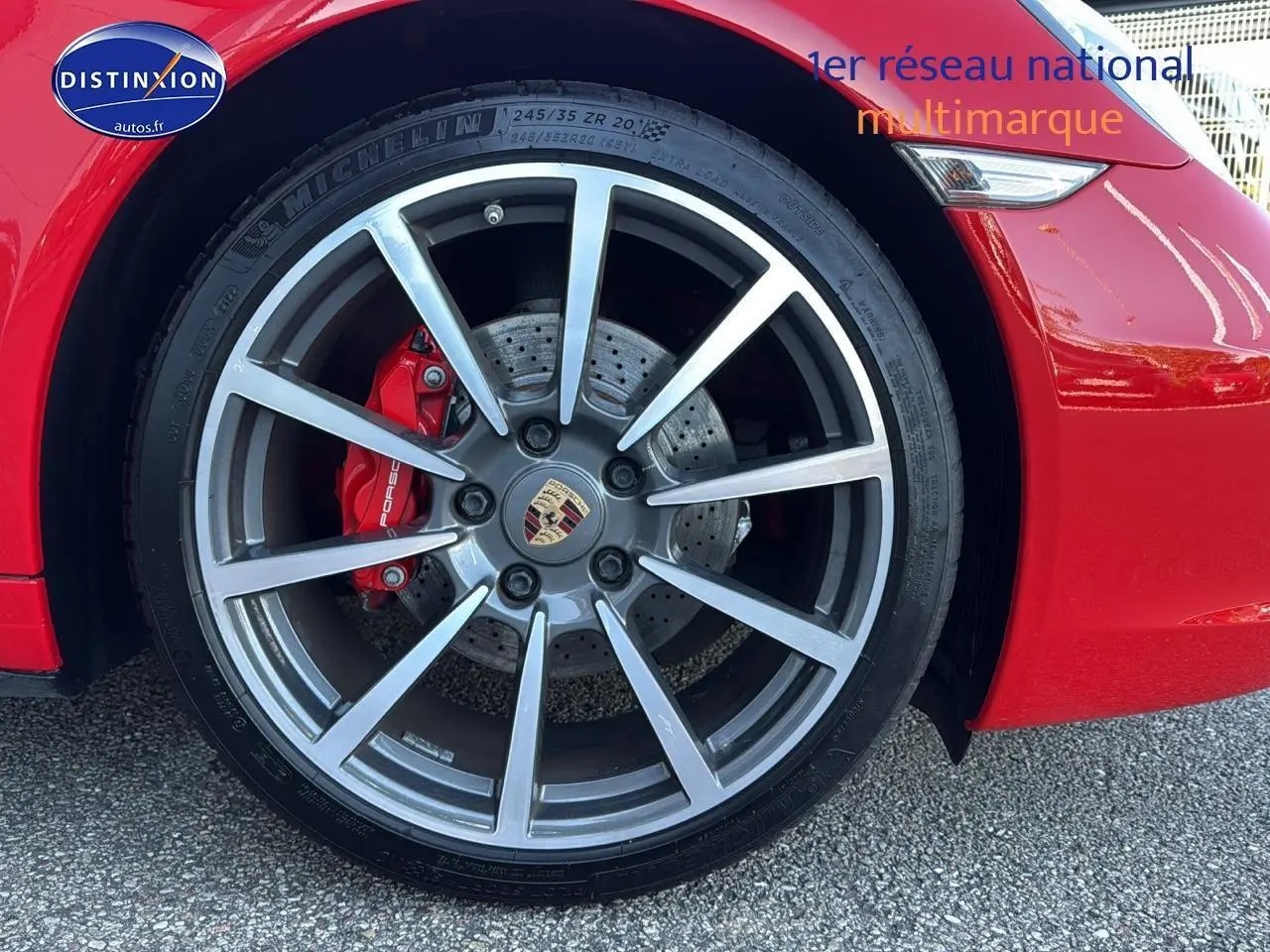 Gros plan sur la roue avant gauche de la Porsche 911 rouge (991) avec étrier de frein rouge et jante alu multibranches.