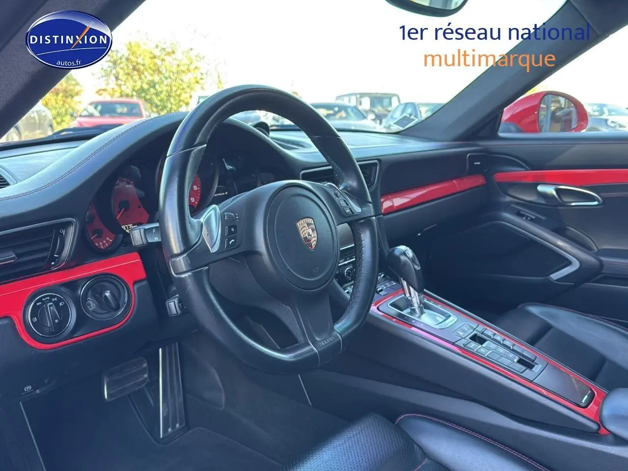 Vue intérieure côté conducteur de la Porsche 911 (991) Carrera 4 PDK 2013, avec tableau de bord et inserts rouges.
