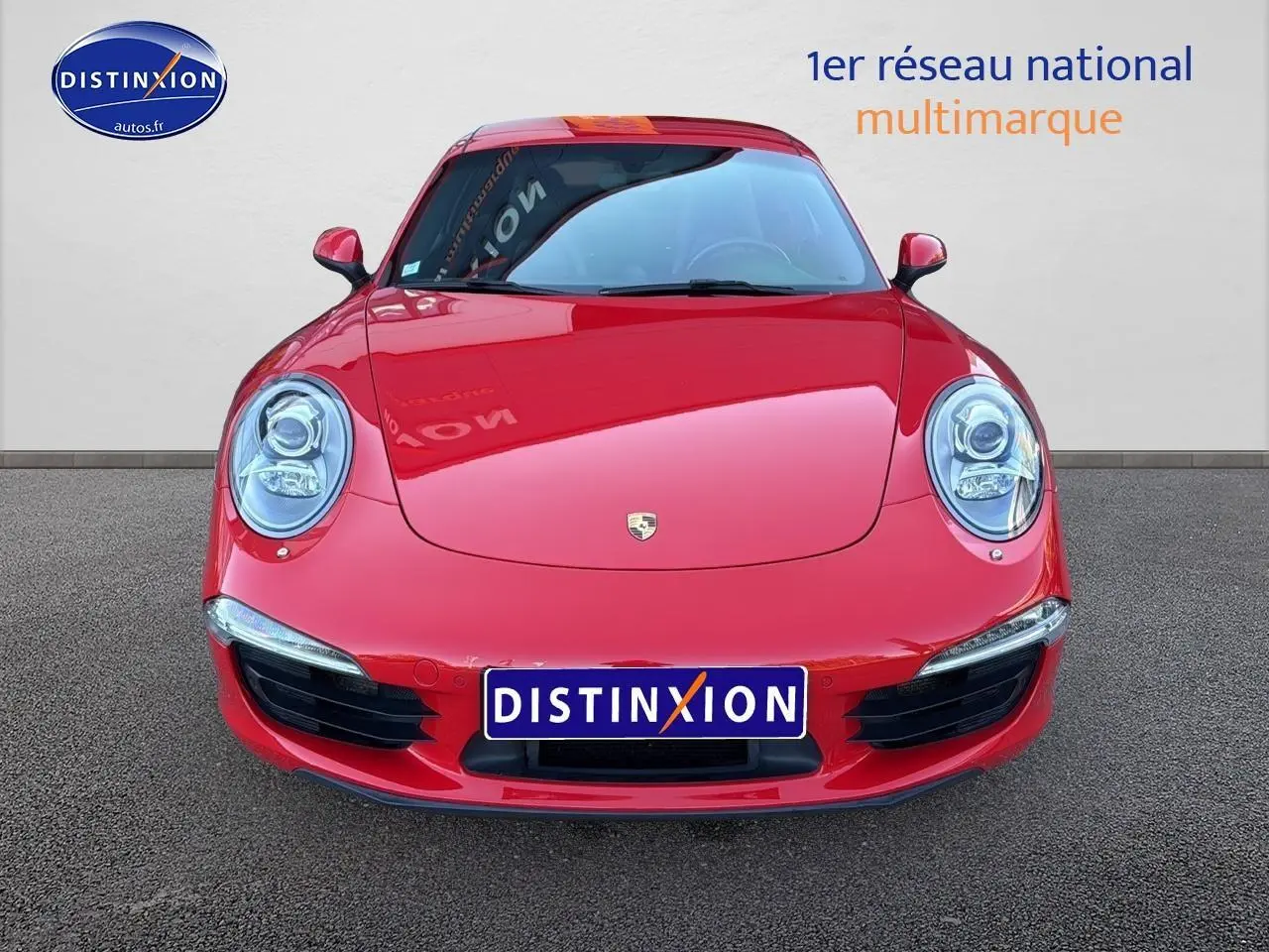 Vue frontale d'une Porsche 911 (991) Carrera 4 PDK rouge avec phares ronds et calandre basse noire.