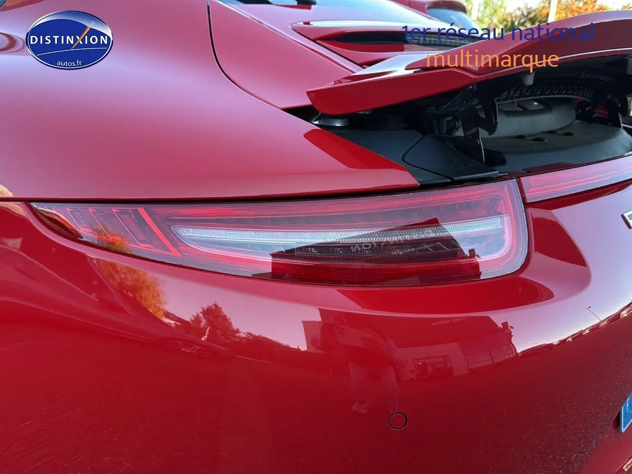 Gros plan sur le feu arrière droit et le becquet relevé d'une Porsche 911 Carrera 4 rouge de 2013.