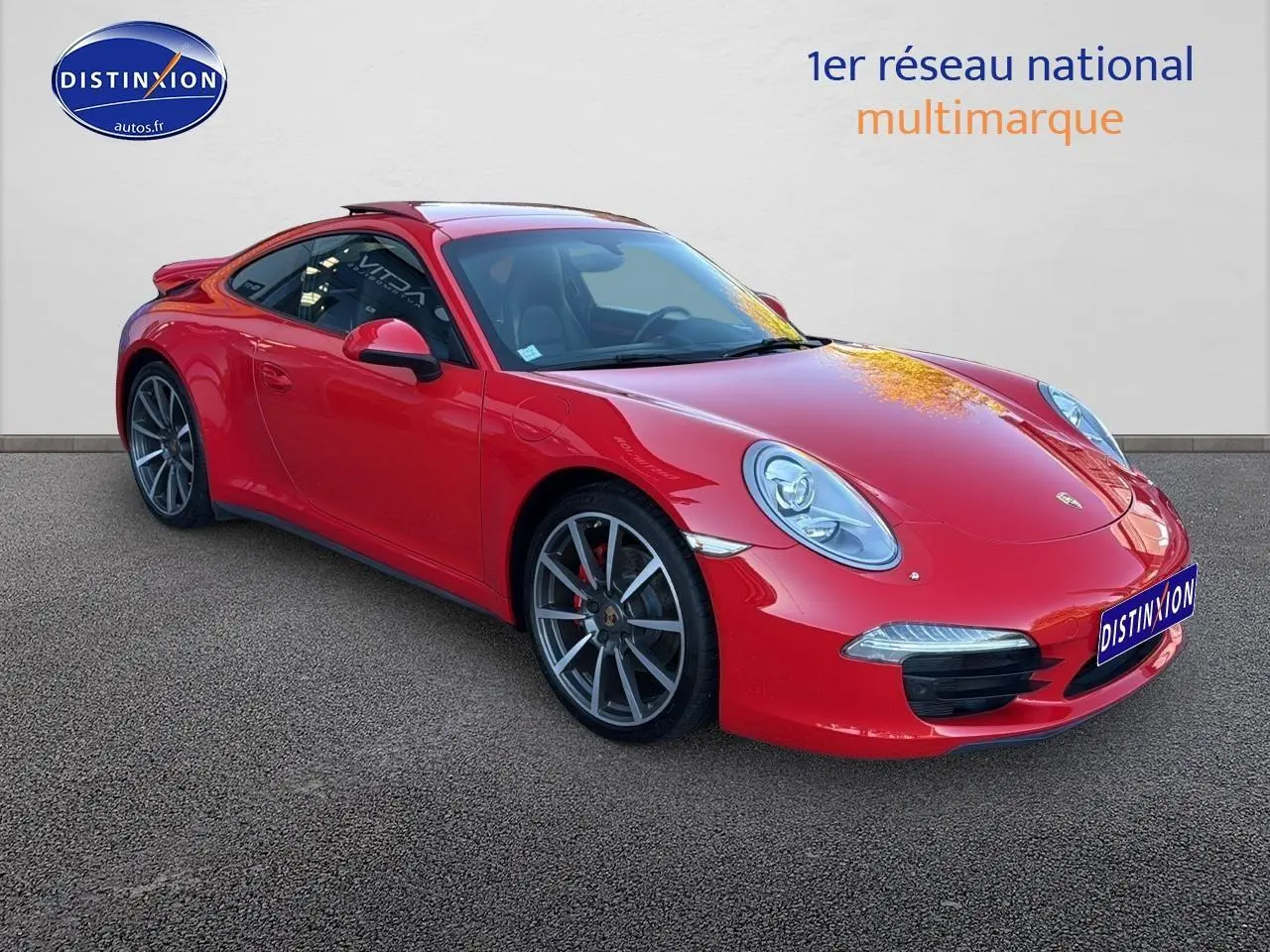 Porsche 911 (991) Carrera 4 rouge vue 3/4 avant droit avec jantes alu et becquet arrière visible.