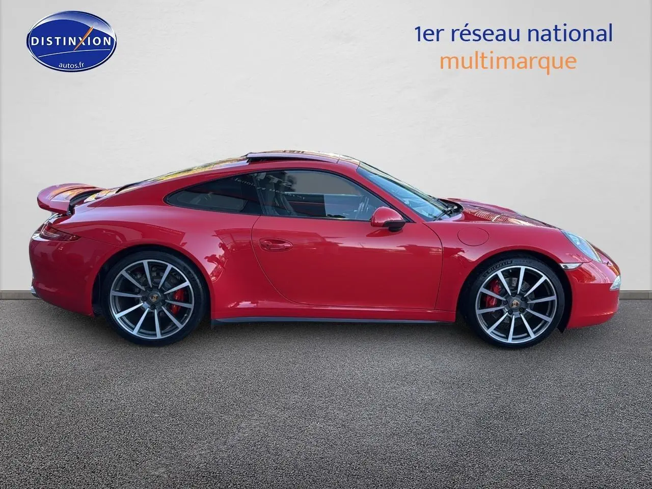 Profil droit d'une Porsche 911 (991) Carrera 4 PDK rouge avec jantes alu et becquet arrière déployé.