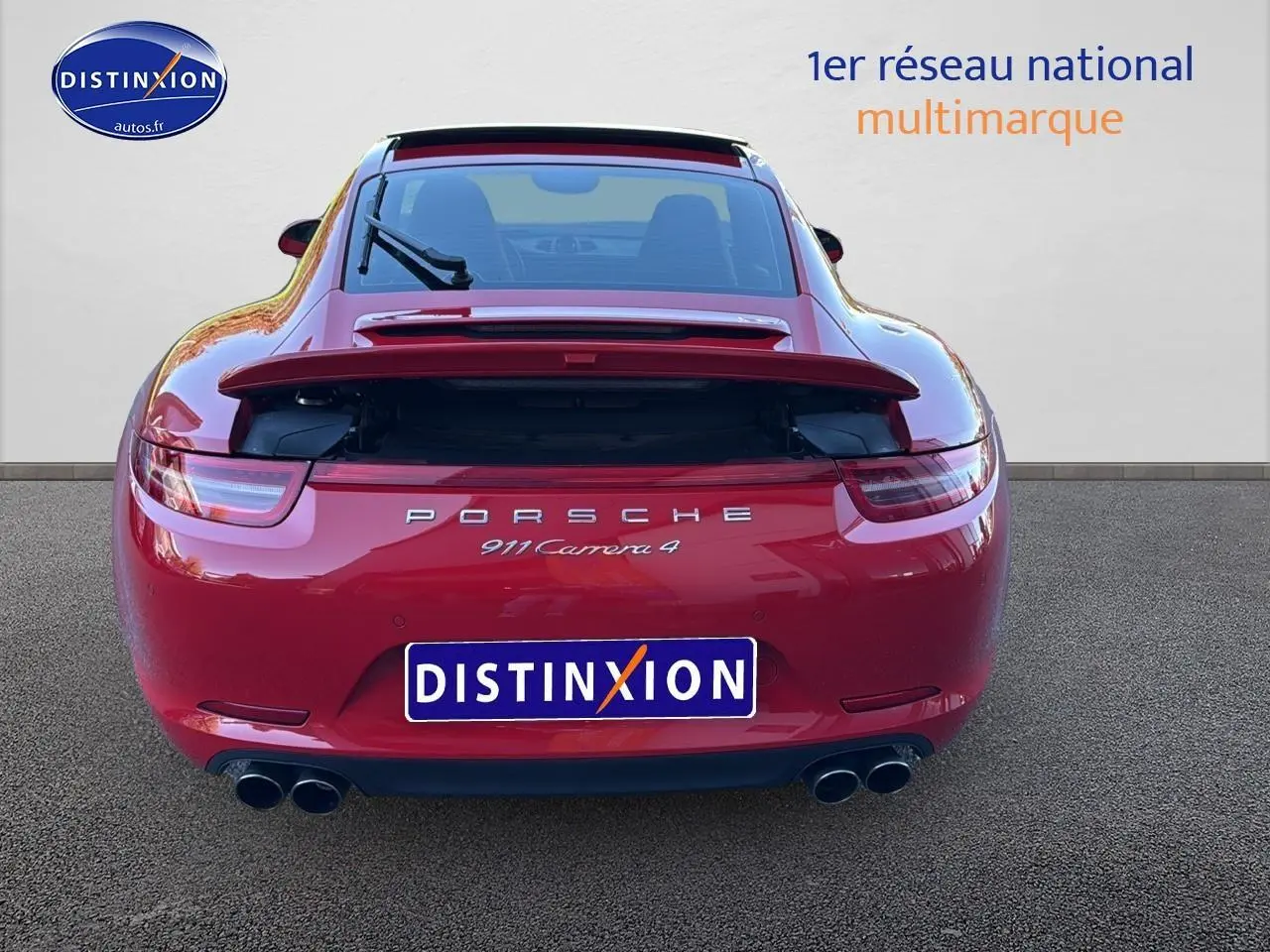 Vue arrière d'une Porsche 911 Carrera 4 rouge de 2013 avec becquet relevé et double sortie d'échappement chromée.