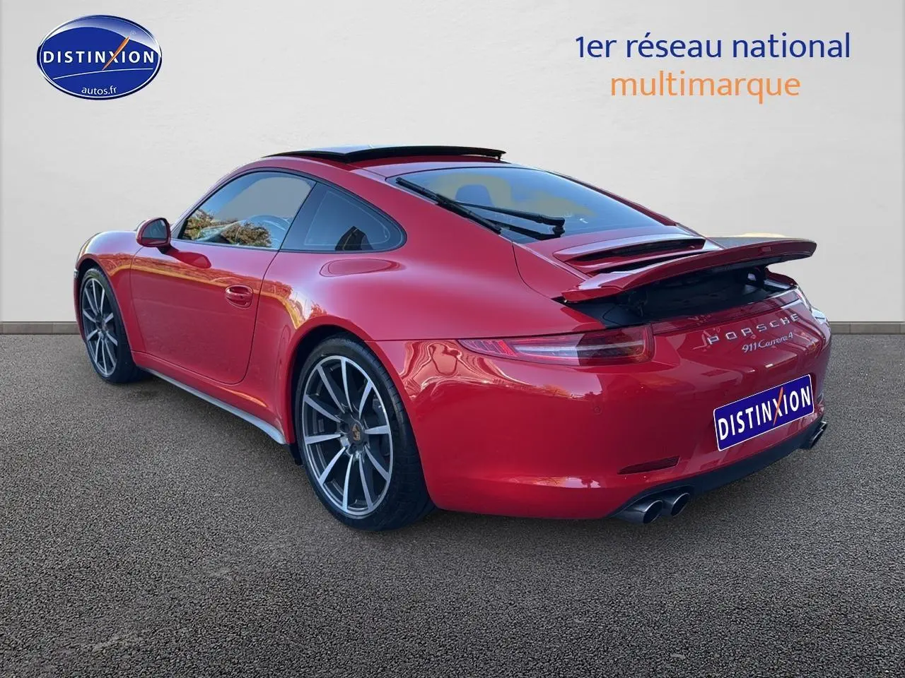 Vue 3/4 arrière droite d'une Porsche 911 Carrera 4 rouge avec becquet arrière déployé et jantes alu.