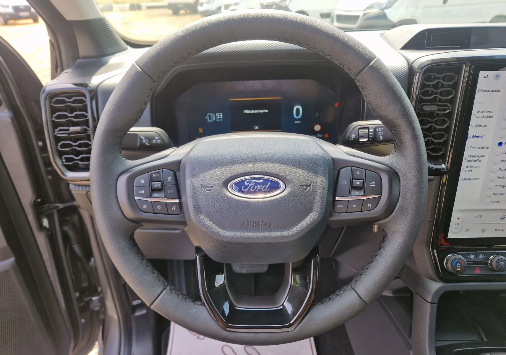 Vue centrée sur le volant cuir du Ford Ranger Super Cabine gris carbone, avec tableau de bord numérique et écran tactile visible.