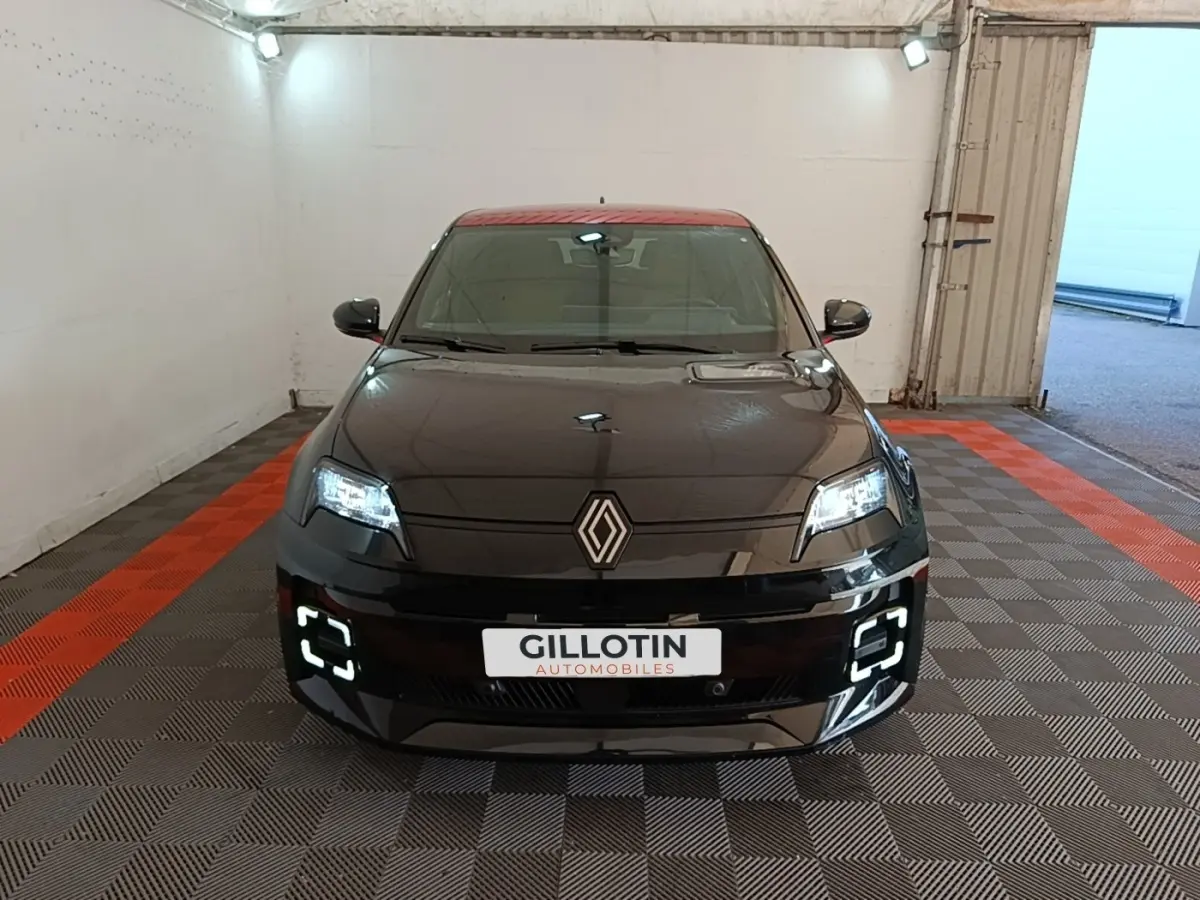 Vue avant d'une Renault R5 électrique 2024 noire avec toit rouge et feux LED allumés en intérieur.