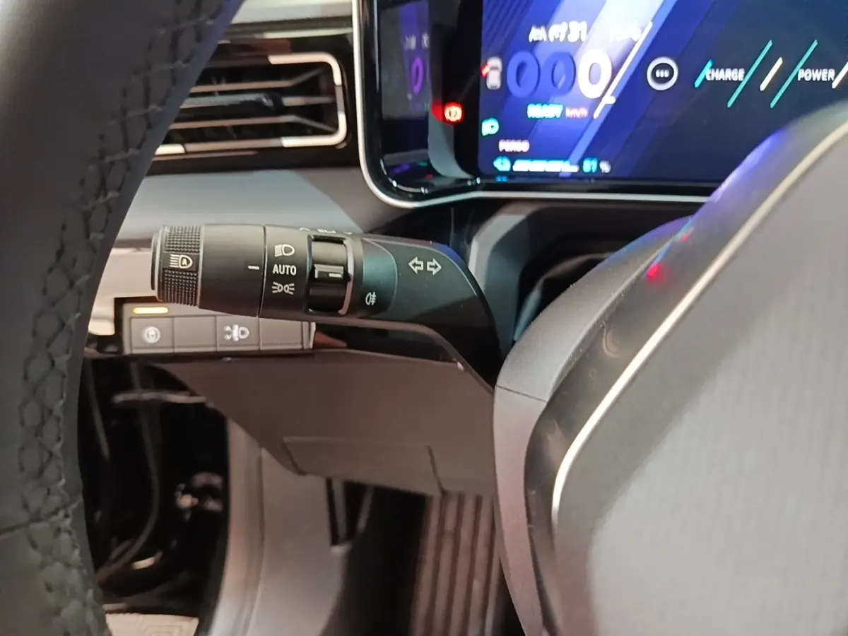 Vue intérieure rapprochée du combiné d'instruments numérique et commande des phares sur Renault R5 Iconic 2024, tableau de bord noir.