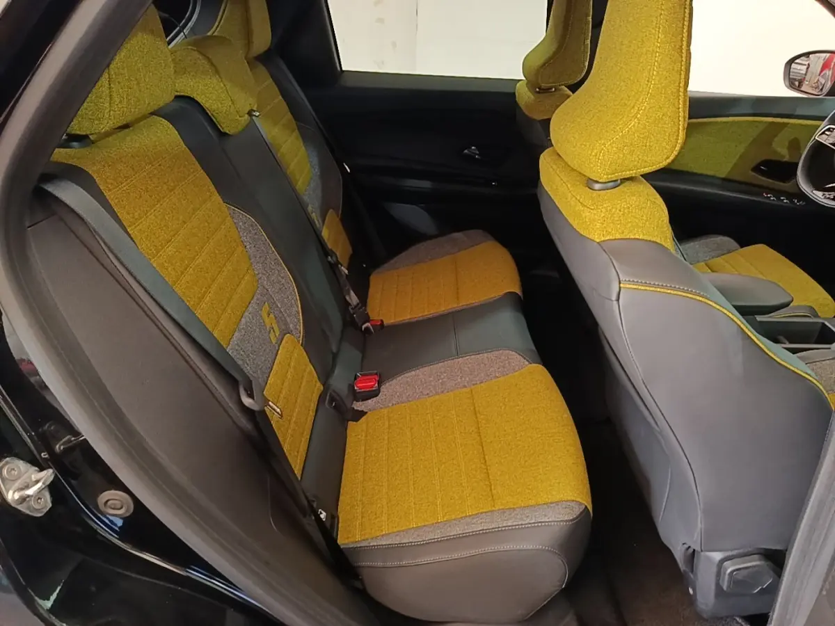 Vue intérieure côté gauche montrant les sièges arrière jaunes et gris du Renault R5 Iconic 2024 avec détails textiles.