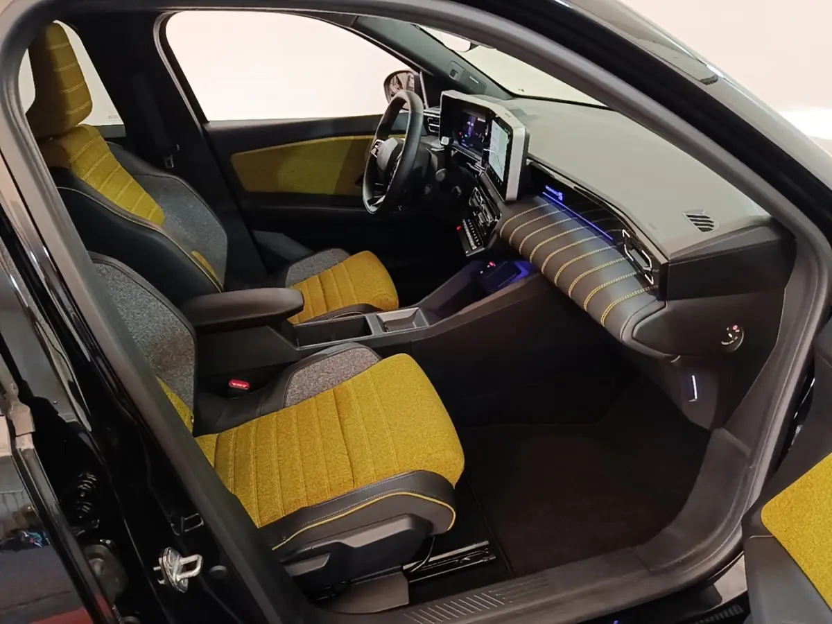 Vue intérieure côté conducteur de la Renault R5 Iconic 2024 avec sièges jaunes et tableau de bord moderne noir.