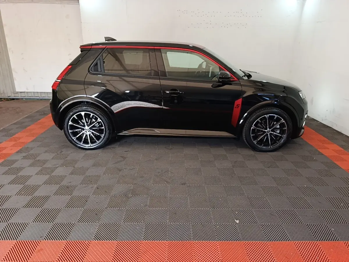 Profil côté gauche d'une Renault R5 Iconic 2024 noire avec détails rouges et jantes noires stylisées.
