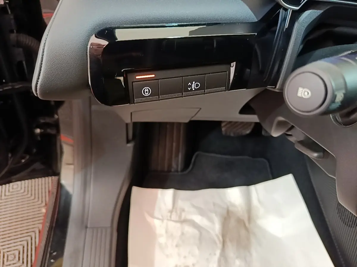 Vue rapprochée côté gauche du tableau de bord noir avec boutons de réglage des phares et verrouillage sur Renault R5 électrique 2024.
