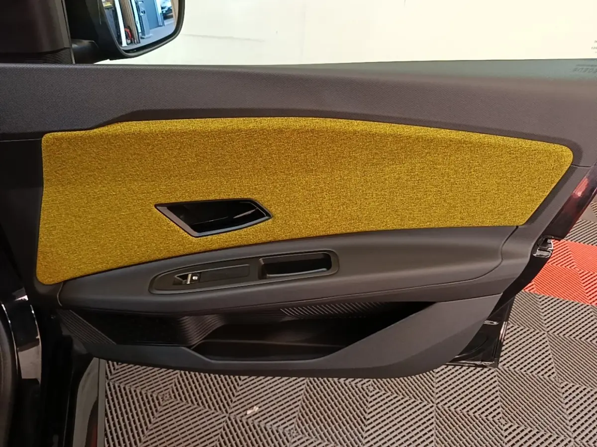 Vue intérieure côté gauche de la porte avant Renault R5 2024 avec insert textile jaune moutarde et garniture noire.
