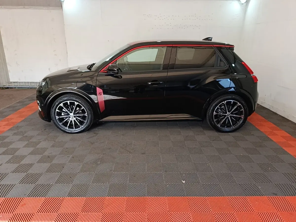 Profil gauche d'une Renault R5 Iconic électrique noire avec détails rouges et jantes noires stylisées.