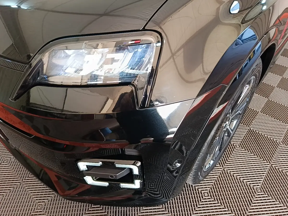 Gros plan sur l'avant droit noir brillant de la Renault R5 électrique 2024, mettant en valeur le phare LED et la roue.