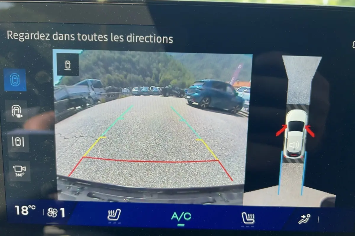 Écran de caméra 360° de la Renault Clio gris rafale montrant la vue arrière en stationnement avec repères colorés.