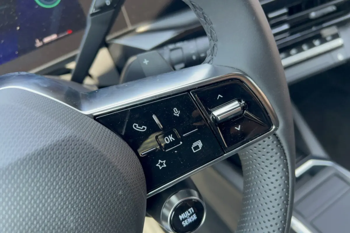 Gros plan sur les commandes multifonctions du volant de la Renault Clio gris rafale, version 2026.