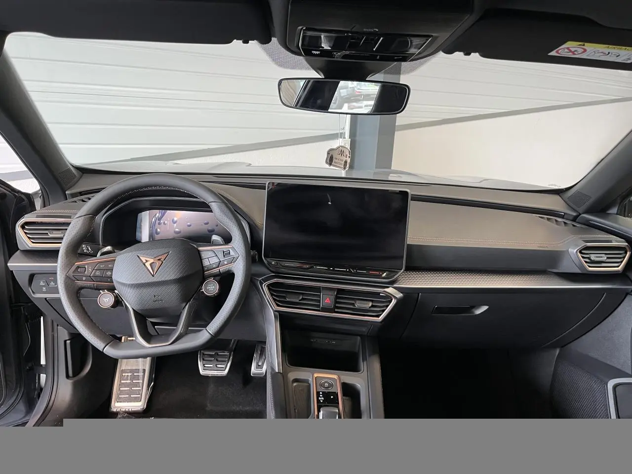 Vue avant de l'habitacle du CUPRA Formentor gris clair, volant cuir, écran tactile central et finitions cuivrées.