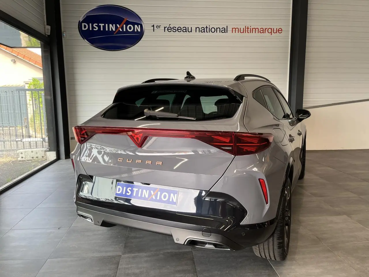 Vue 3/4 arrière droite du CUPRA Formentor gris clair avec signature lumineuse Tri-LED et double sortie d'échappement noire.