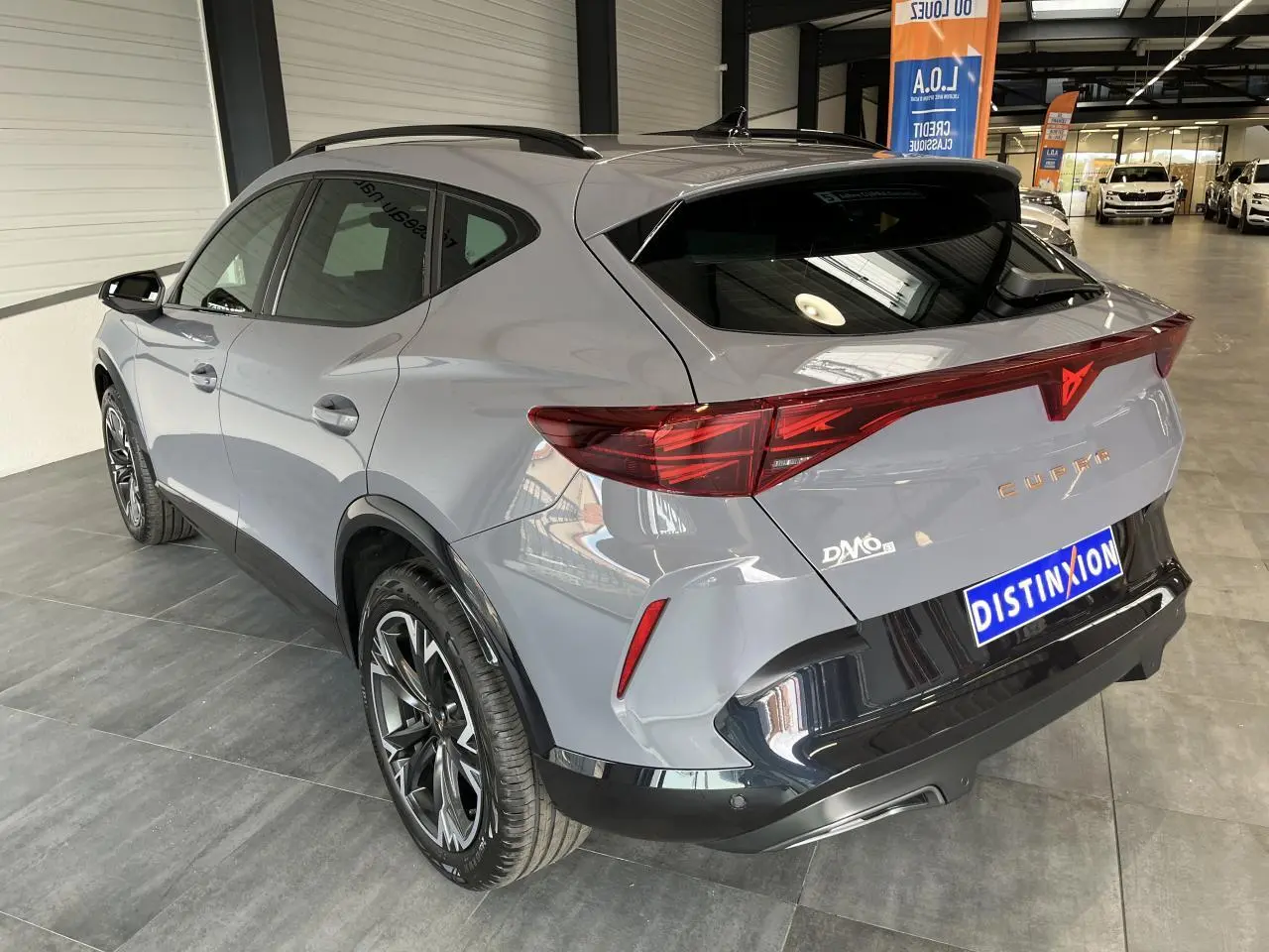 Vue 3/4 arrière droite du CUPRA Formentor gris clair avec bandeau lumineux arrière et jantes alliage 18 pouces.