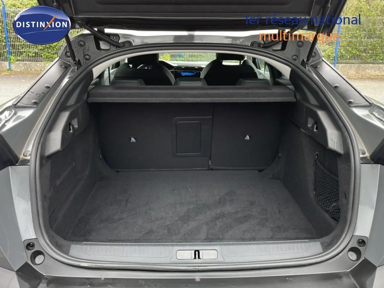 Coffre ouvert vu de l'arrière d'une Peugeot 408 gris selenium metal, montrant un espace de chargement spacieux et propre.