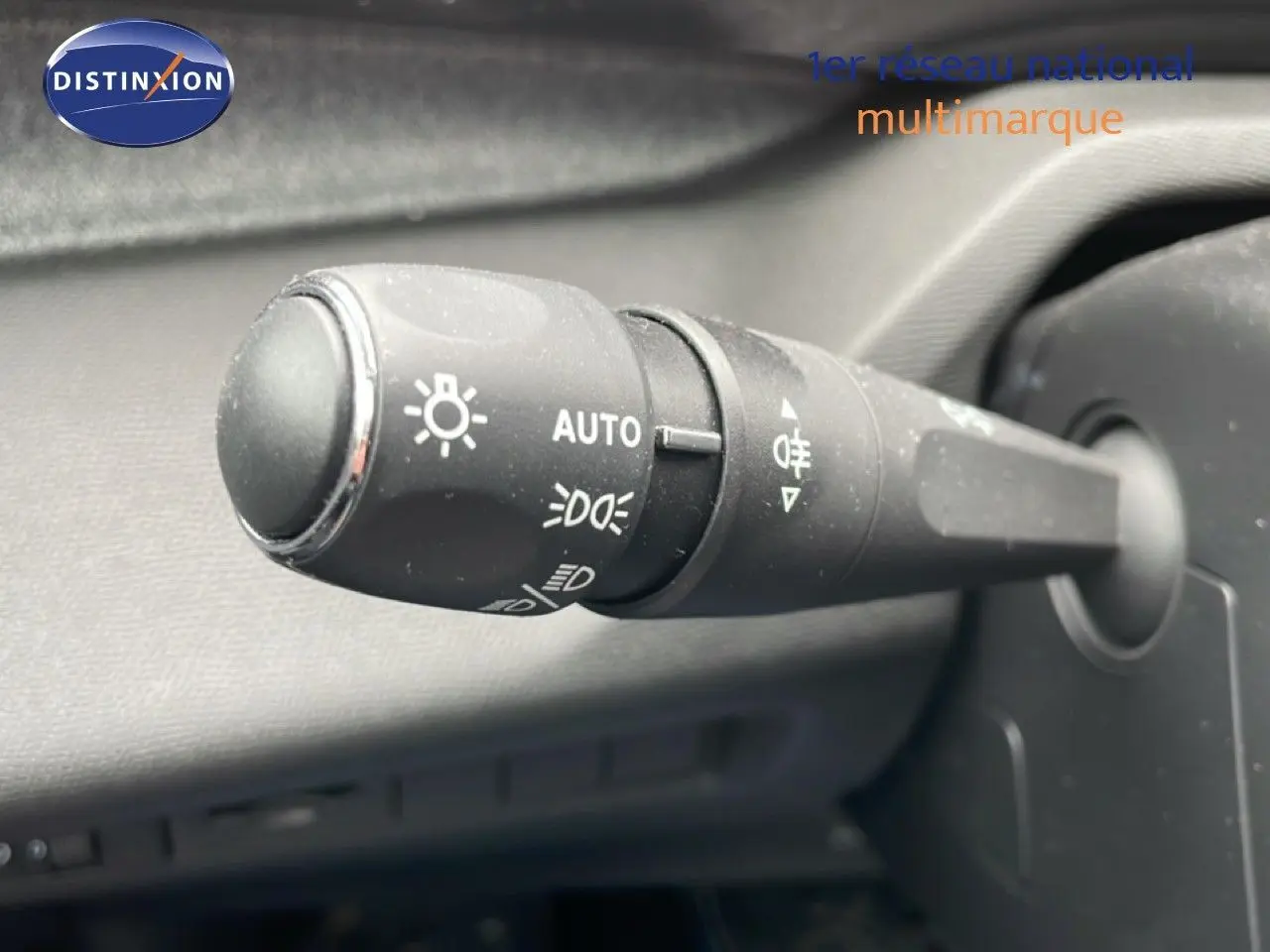 Gros plan sur la commande des feux automatique à gauche du volant dans un Peugeot 408 gris Selenium 2025.